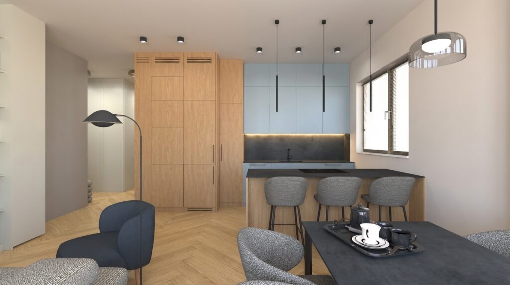 Projekt wnętrza nowoczesnego salonu z aneksem kuchennym i funkcjonalną wyspą. Zabudowa kuchenna łączy drewniane oraz jasne fronty, a drewniana podłoga w jodełkę, designerskie oświetlenie i minimalistyczne wyposażenie podkreślają ciepły charakter wnętrza.